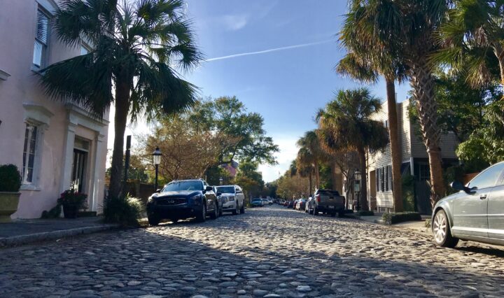 Cobbled Streets of Charleston South Carolina with palm trees and buildings to the side.