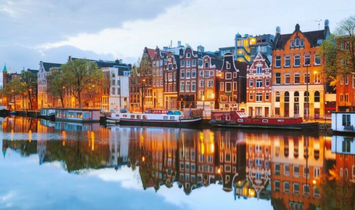 The Netherlands, lit buildings along channel of water glistening with reflection of the buildings