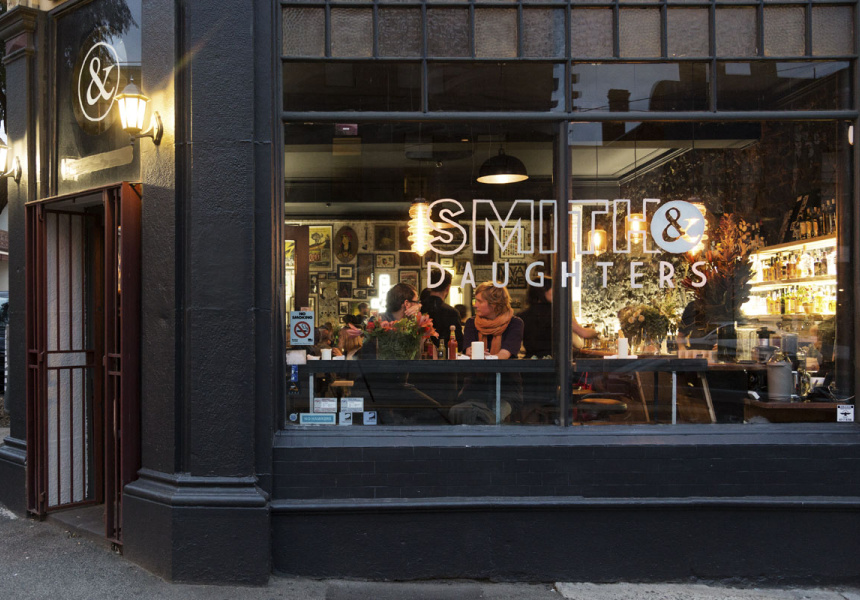 Голям прозорец с надпис „Smith & Daughters“ отпред и хора, които се хранят на маси в добре осветена стая