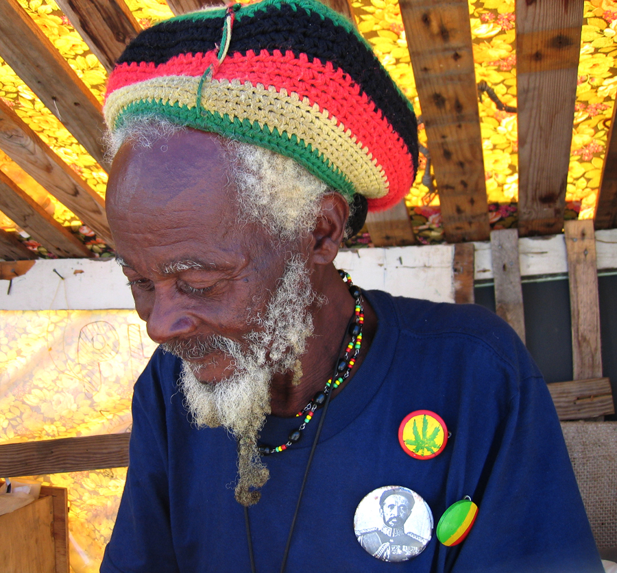 An old man of the Rastafari religion wears a rastacap on his head.