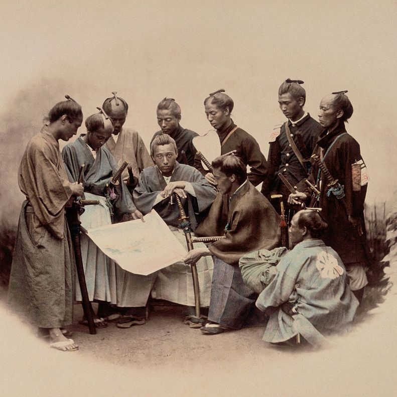 Nine samurai are sitting around a large piece of rolled-out paper, discussing the Bushido, to conclude the content entry of the samurai in feudal Japan.