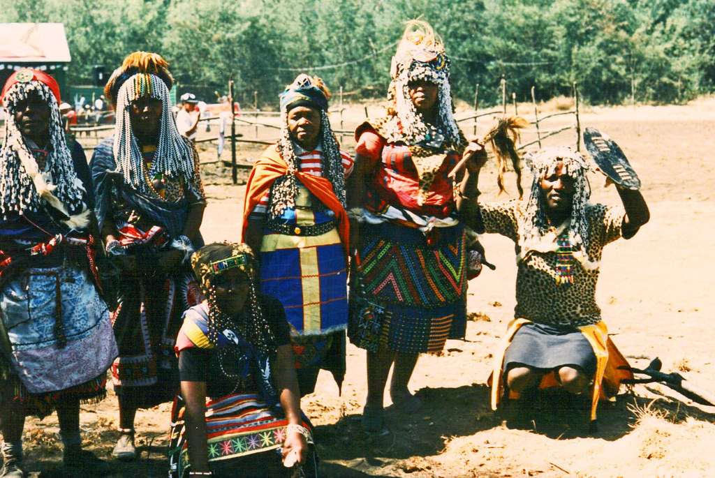 Fem insangomer set i en afrikansk landsby, klædt i traditionelt og kulturelt passende troldlæge-slid.