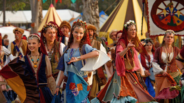 Romani women dressed in traditional clothing and dancing during a festival.
