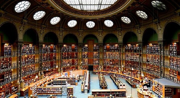 Et bredt blik på indersiden af ​​Nationalbiblioteket i Frnance med et glasloft og flere hylder med bøger, der ligger på den cirkulære væg.