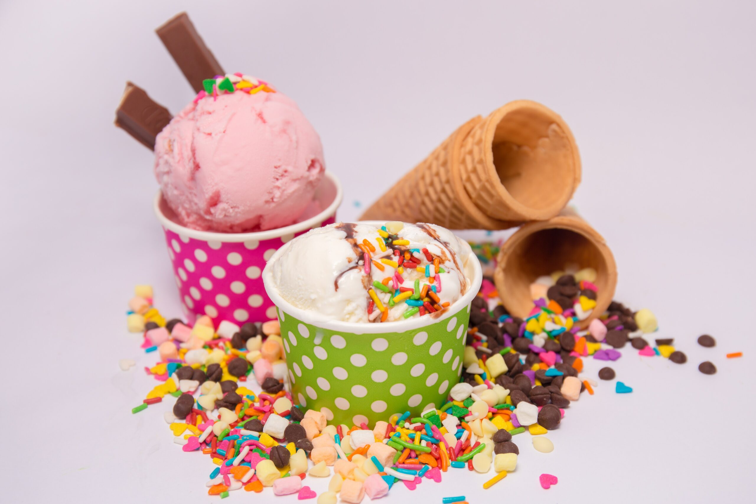 Конуси за сладолед над преливащи се с пръски, купички със сладолед