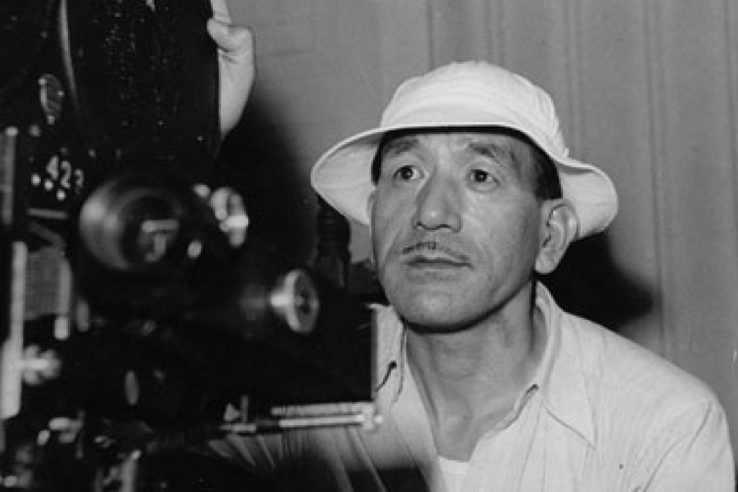 a black and white picture of Yasujiro Ozu sitting behind the camera
