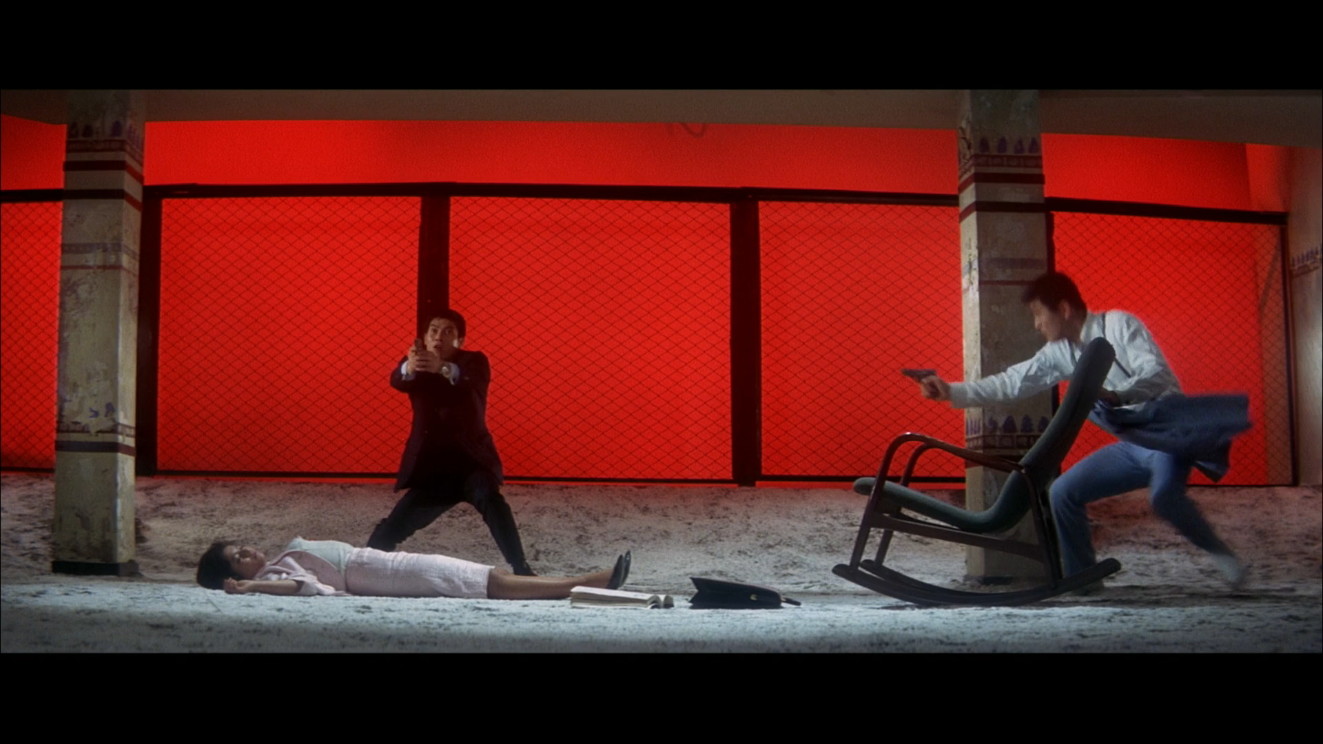 a colored picture of a scene from the yakuza movie called Tokyo Drifter, where two man are shooting and one woman is shot, lying on the floor