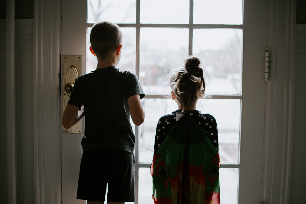 Image of tow children looking out the window during quarantine