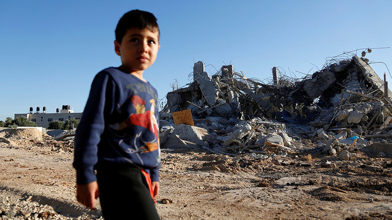 A boy walks past a demolished Palistinian house a