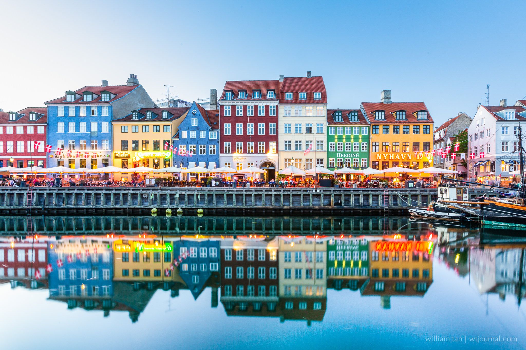 Nyhavn, making a reflection on the water, all lighting opened and loads of people sitting to have their meal