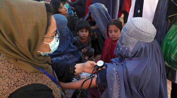 An internally displaced woman from northern provinces, who fled her home due to fighting between the Taliban and Afghan security personnel, has her blood pressure taken after taking refuge in a public park in Kabul, Afghanistan.