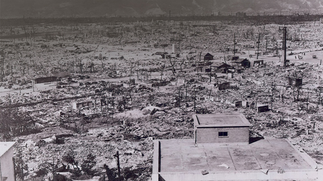 A black and white images showing damage the atomic bomb had on Hiroshima, with homes destroyed and left as rubble and nearly dust. Large trees are gone, roads have disappeared, and a city where people could no longer live. The image depicts the effect on Nagasaki