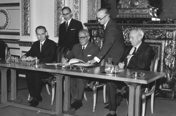 A black and white photograph of world leaders at a rectangular desk, signing the NTP.