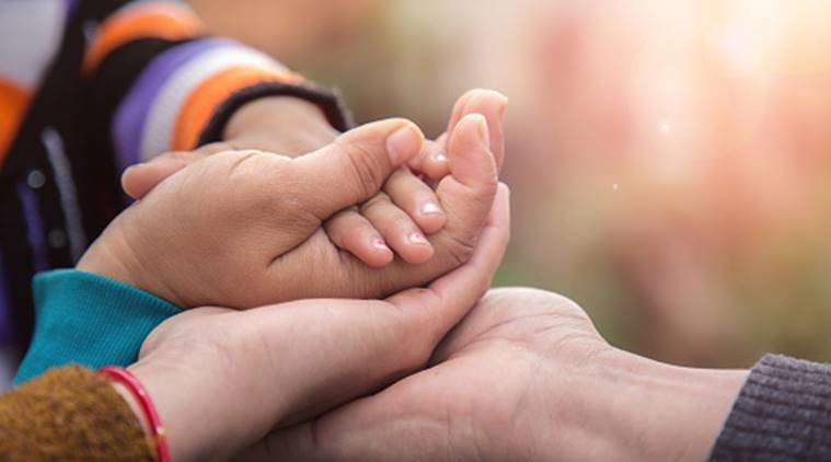 Adoption. Photograph of child's and parent's hands.