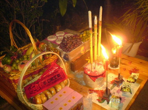 table full of incense sticks, fruits and candles