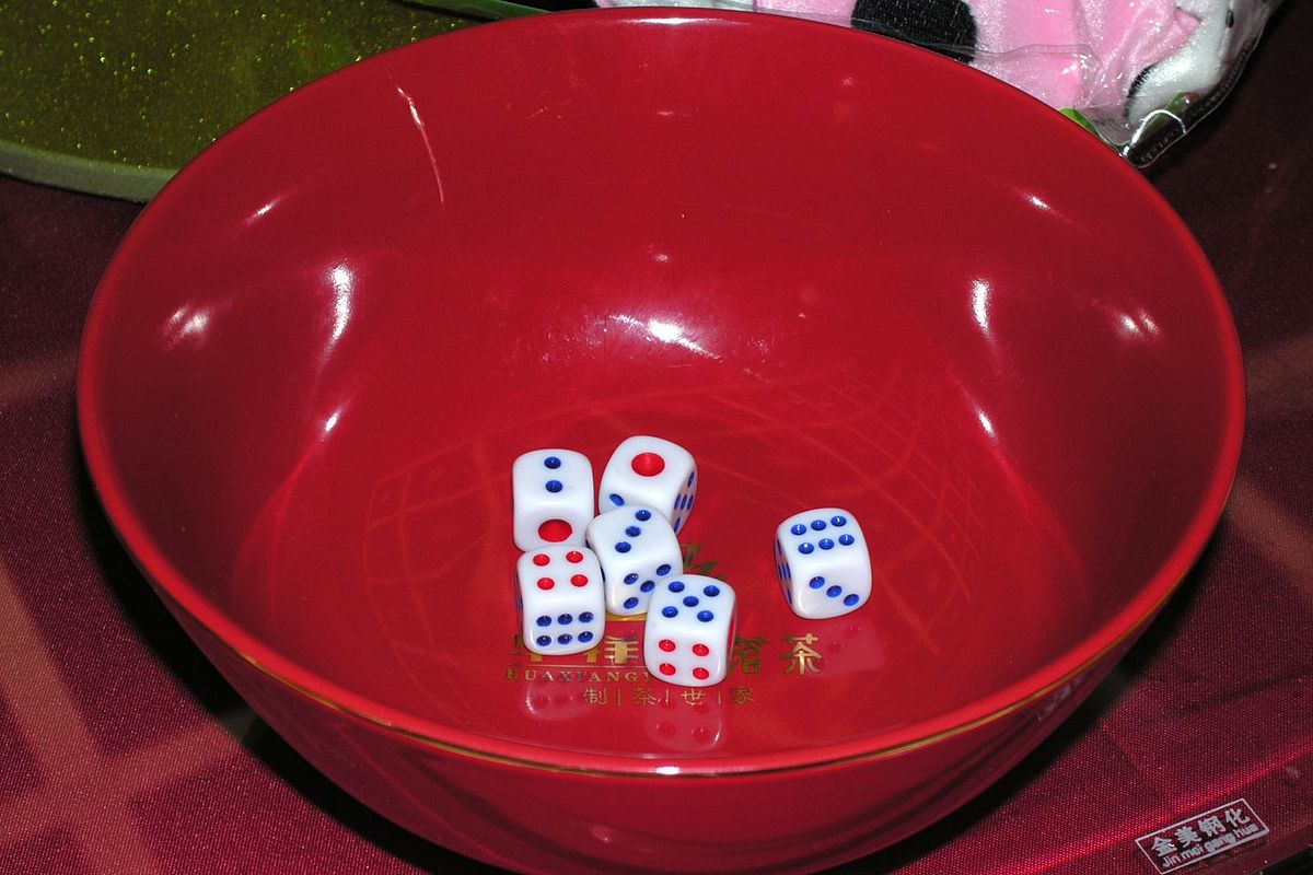 six dice in a red porcelain bowl