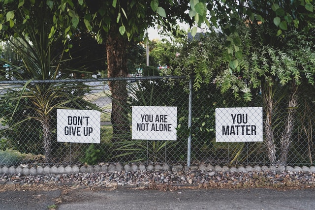 სამი ნიშანი მეტალის ღობეზე: "არ დანებდე", "შენ მარტო არ ხარ" და "შენ მნიშვნელობა გაქვს".