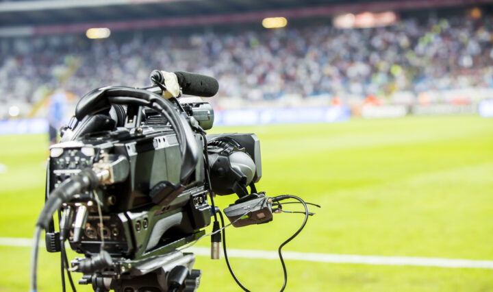 A television camera on the sidelines of a soccer field.