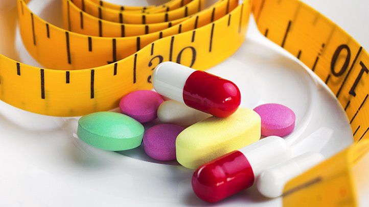 A decorative images showing a bunch of diet medication next to a tape measure.