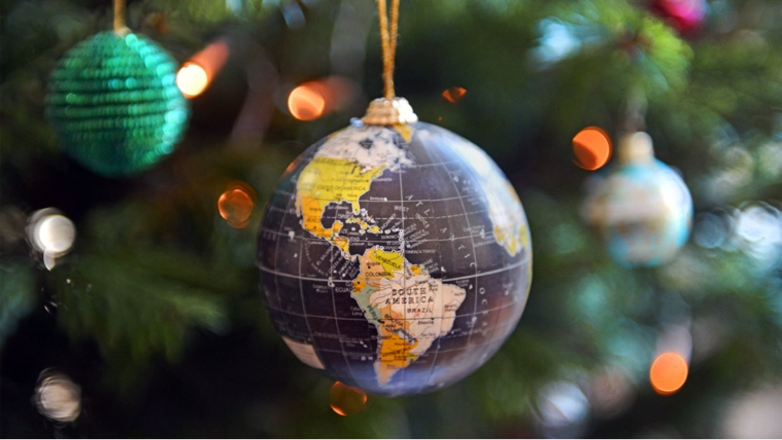 En julekugle med et billede af verden på hænger fra et juletræ