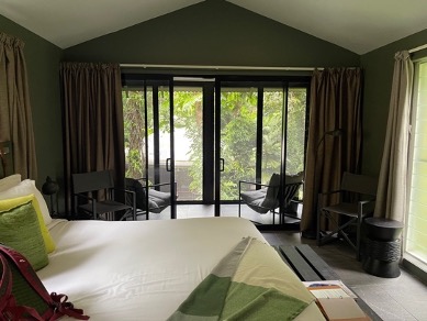 Пастелно-зеленият интериор от Daintree ecolodge с легло и балкон с два стола