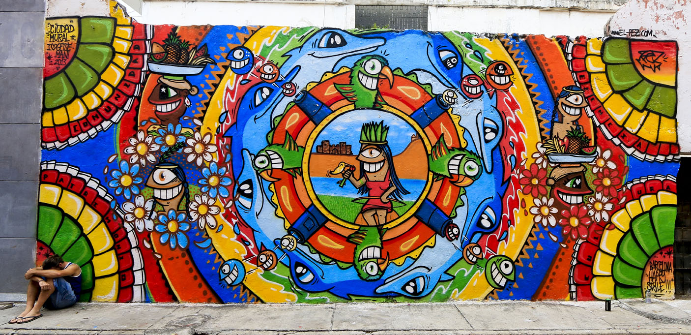 Мъж кляка в ъгъла на цветен уличен стенопис