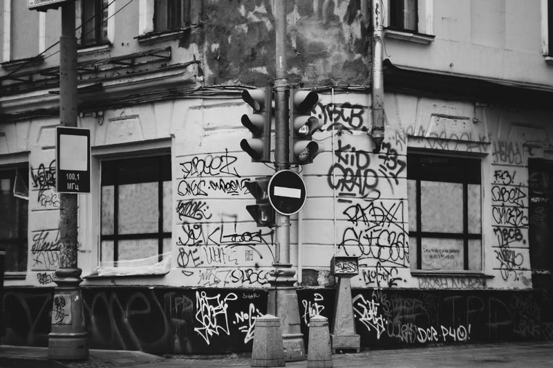 Черно-бяло изображение на ъглова сграда, покрита с етикети с графити