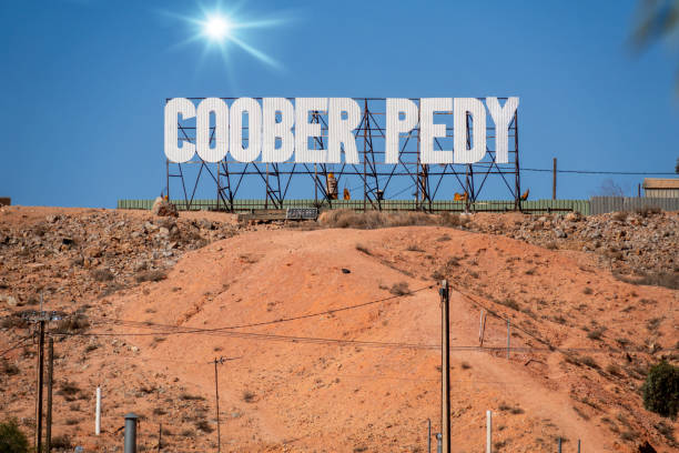 An image of large letters that spell Coober Pedy, on top of a red hill in in south Australia.