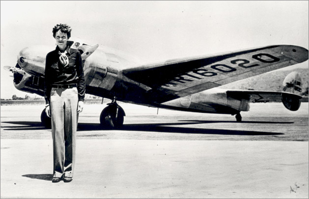 One of the last images of Amelia Earhart on the runway, standing inf ront of her plane.
