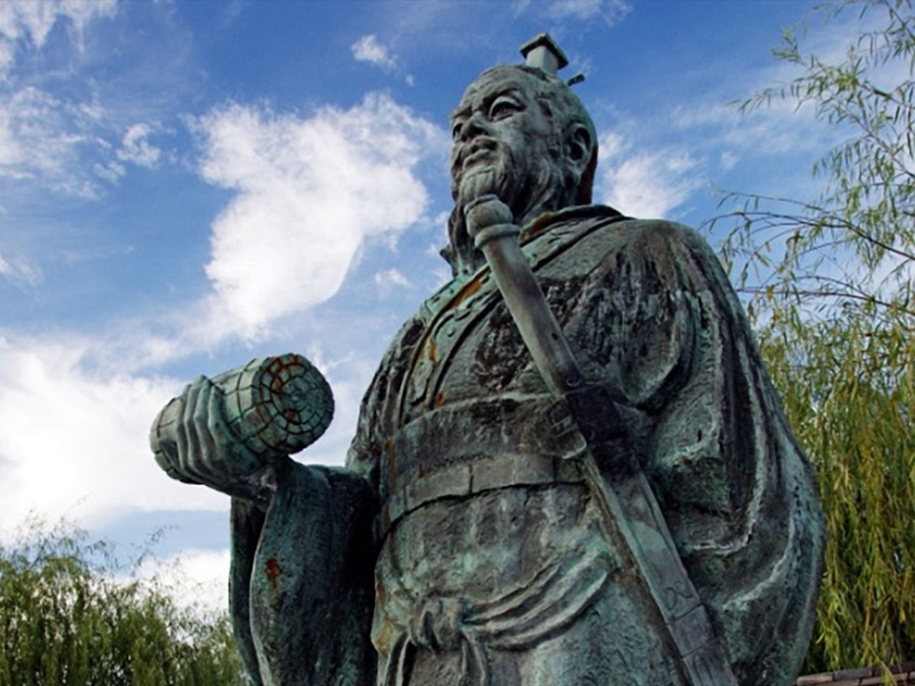 statue of sun tzu holding the art of war