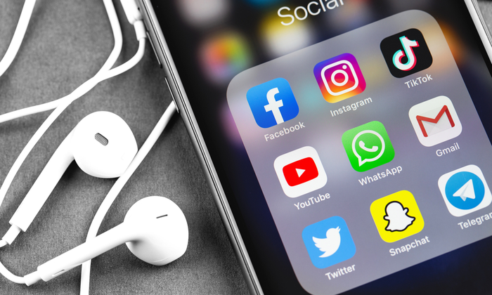 Et billede af en Iphone, med en visning af ikoner, der symboliserer forskellige sociale medieplatforme.