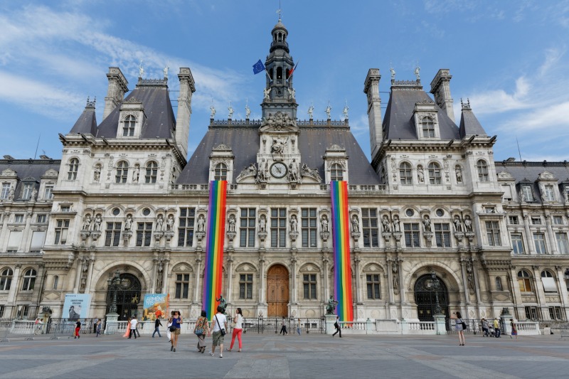 A historic building in Paris, safe for LGBTQIA+ travelers, draped in rainbow flags.
