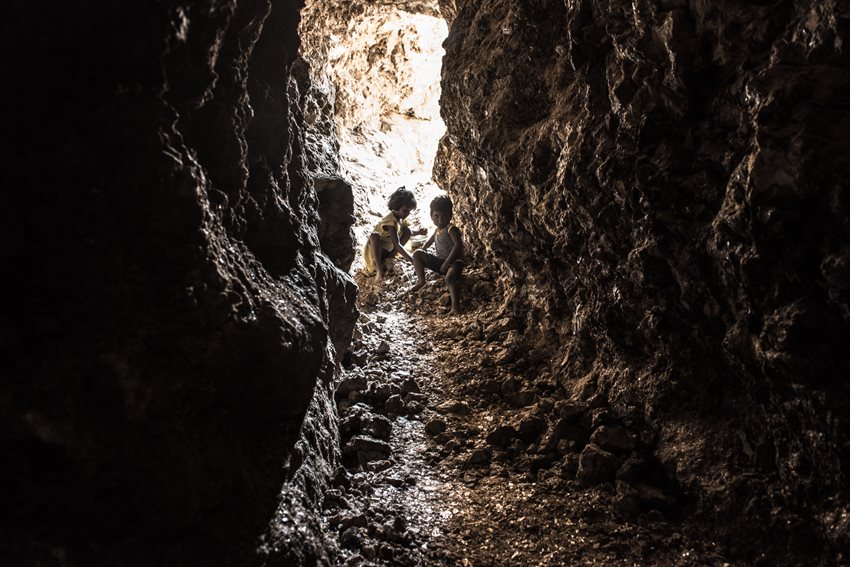Een afbeelding van twee jonge kinderen in een smalle tunnel van een micamijn.