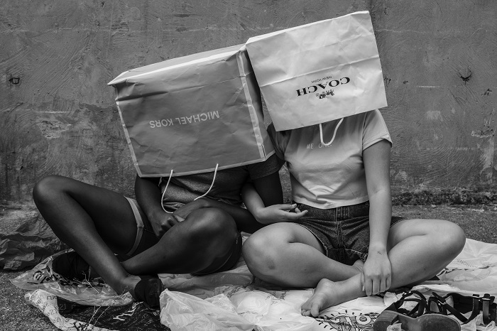 Black and white image of two people with branded shopping bags over their heads
