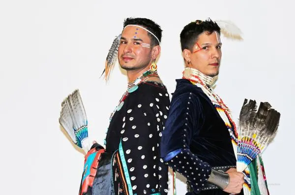 Two-spirit couple stand back to back.