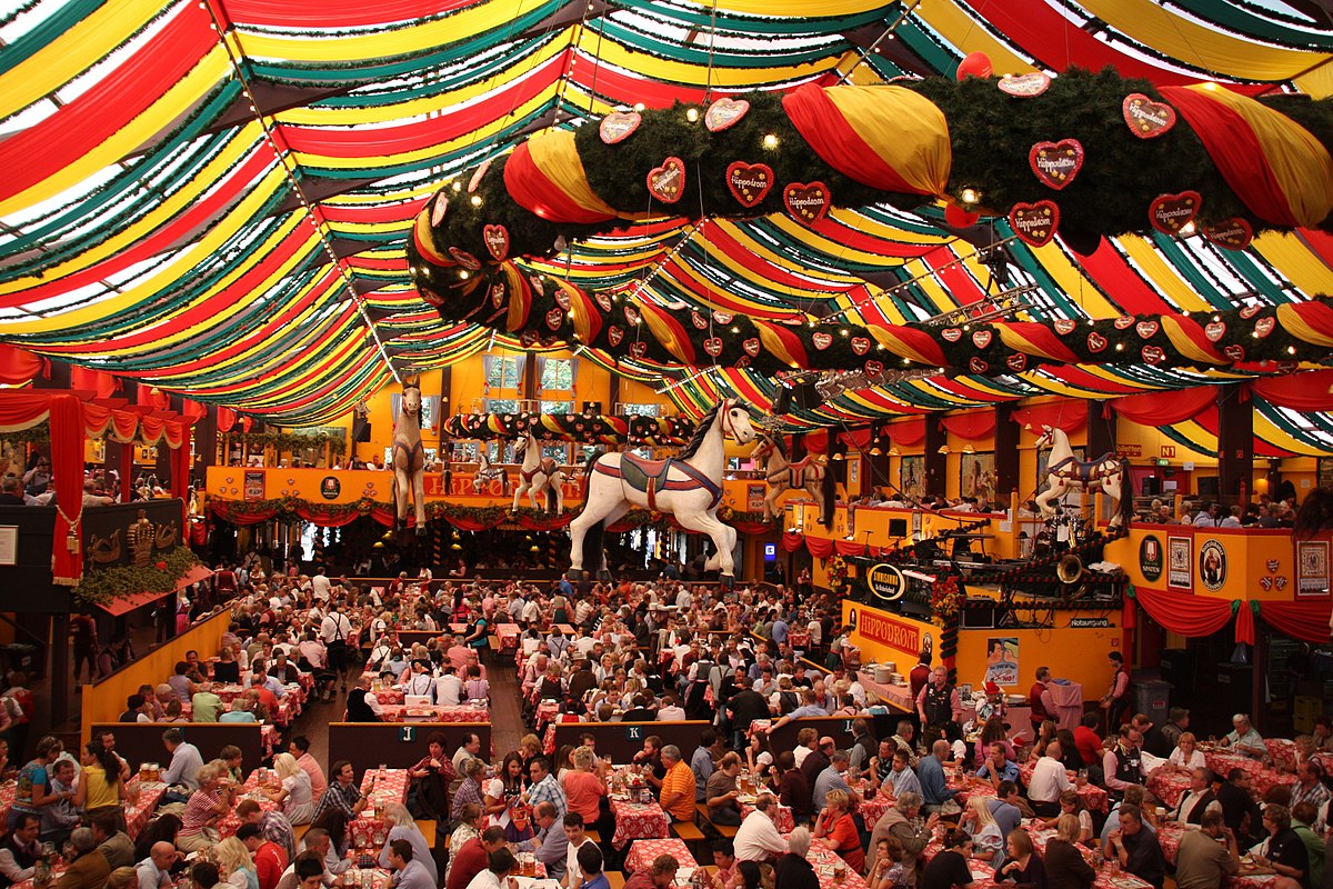 A large crowd of people sitting down at a beer tent during Oktoberfest